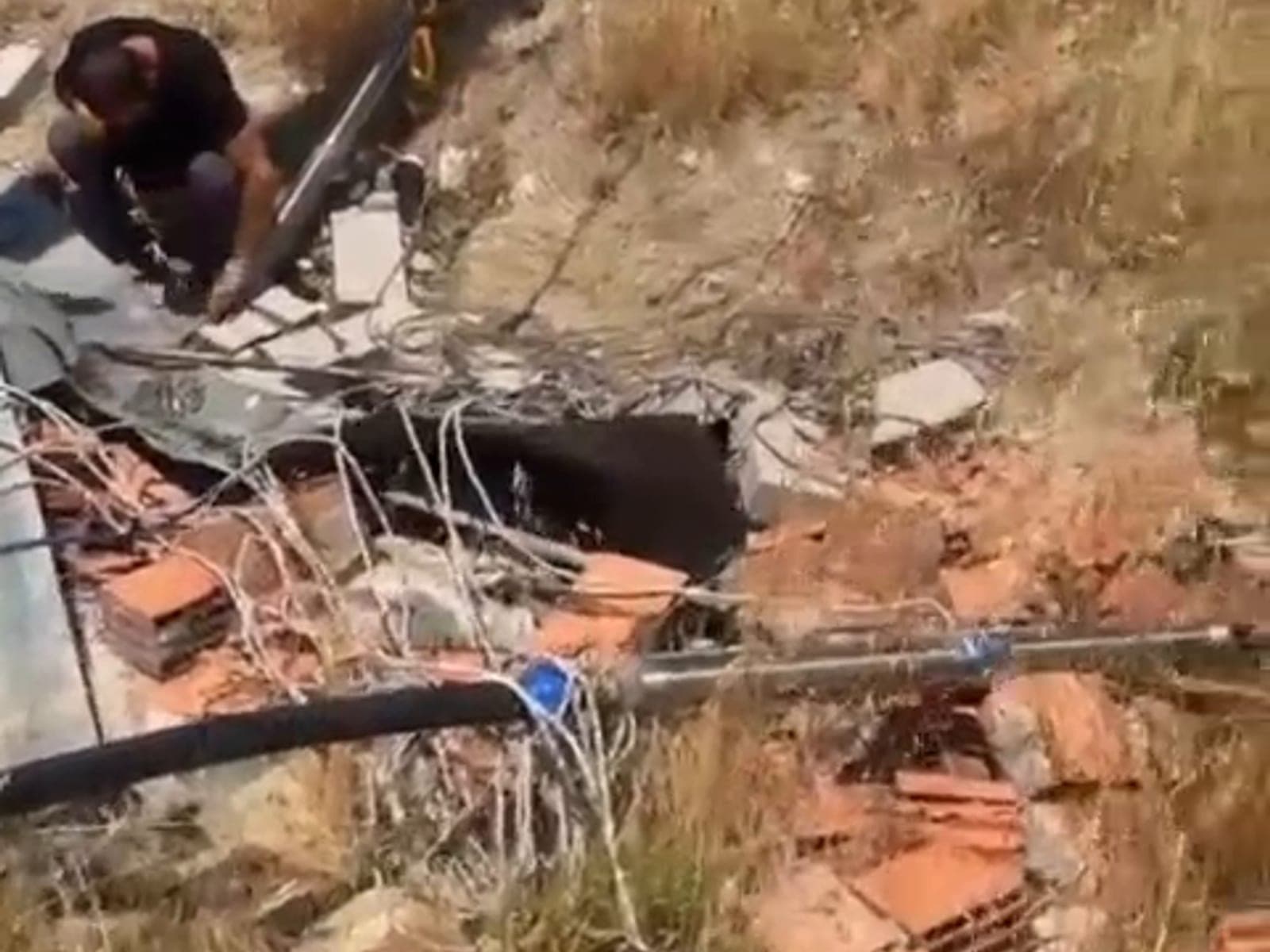 Kuyudan çıkarılmış dolanmış kablo ve siyah polietilen boru, kuyu başındaki kuru zemine serilmiş hâlde duruyor