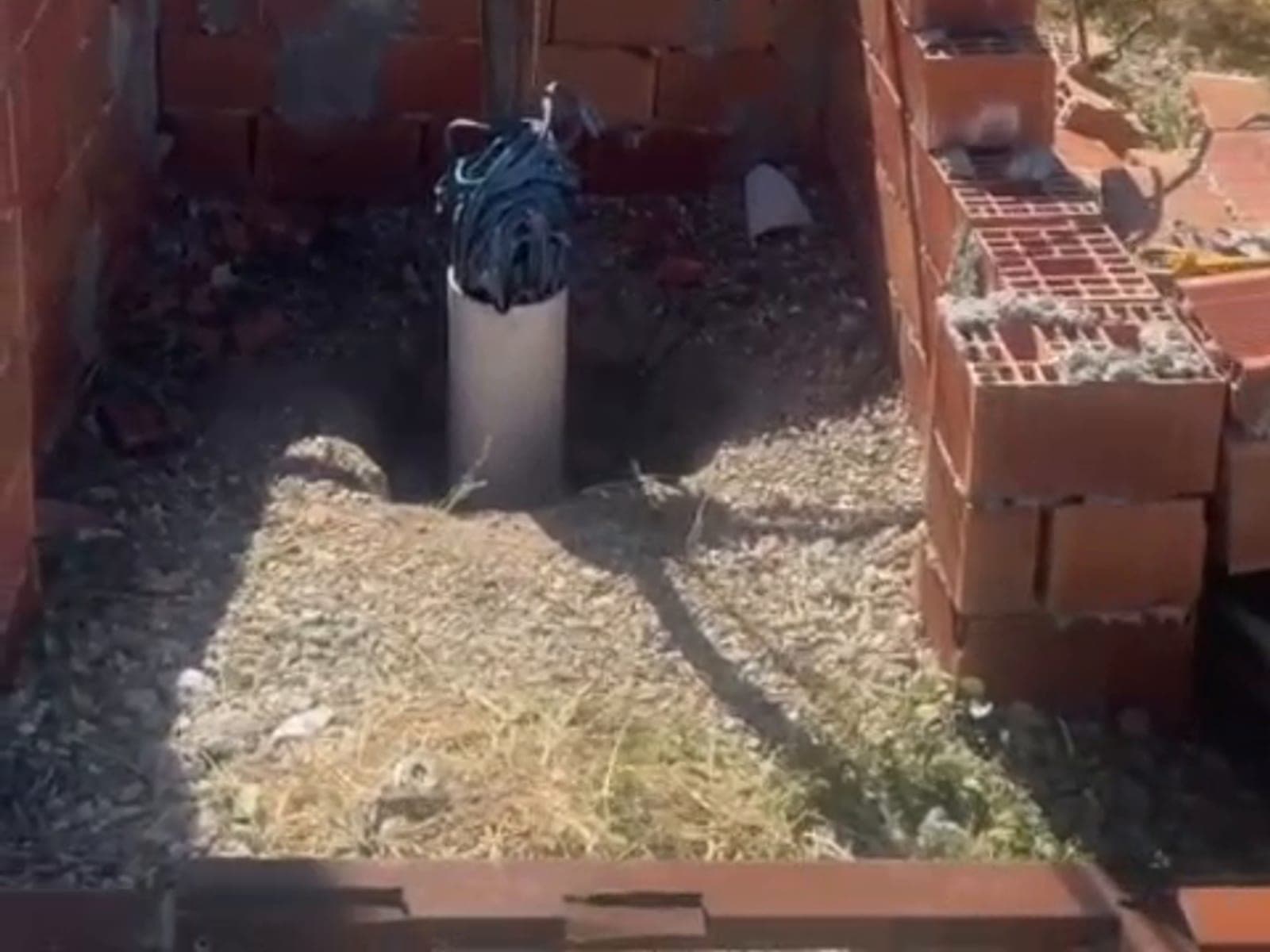 Tuğla duvarla çevrili kuyu ağzındaki boruya inen vinç halatı; boru ağzında maviyle sarılmış kablo demeti duruyor